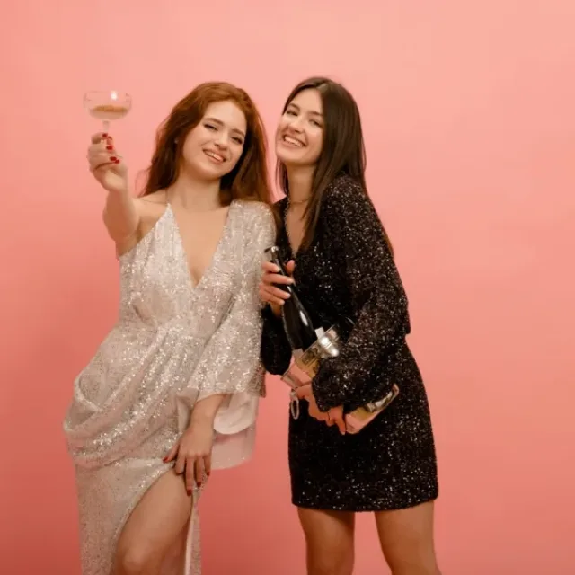 Two young women, one holding up a glass of wine