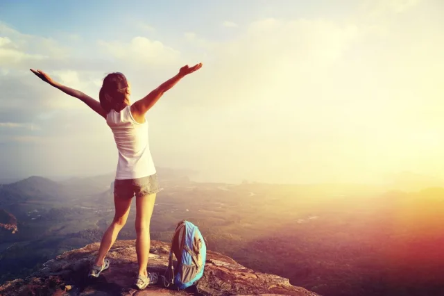 Cheering hiking woman on mountain peak 000058778804 large 1