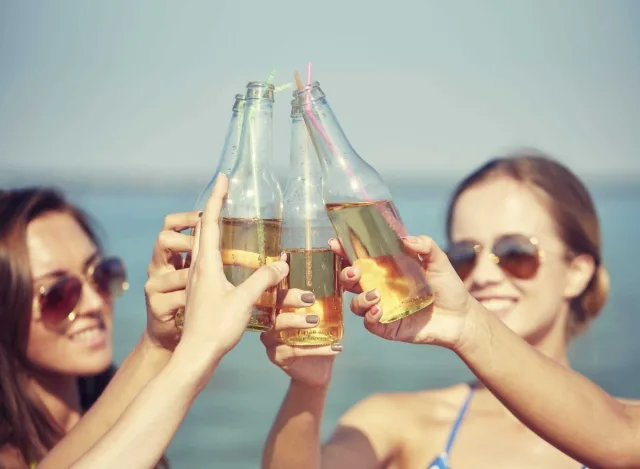 Close up of happy young women with drinks on beach 000069864029 Large 2